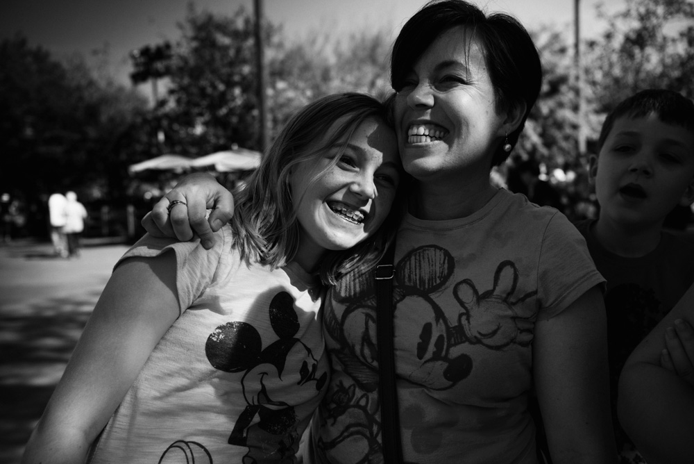 a woman and a girl hugging and laughing wearing mickey mouse shirts