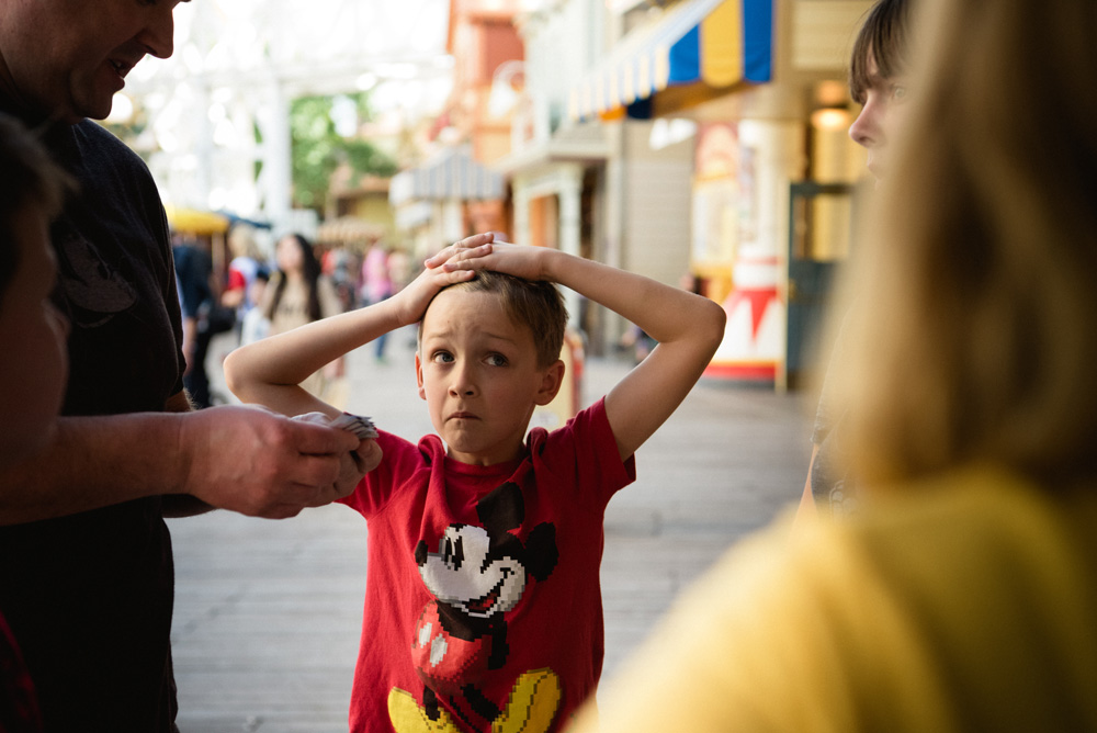 a boy looking sad wearing a red mickey mouse shirt with his hands on his head
