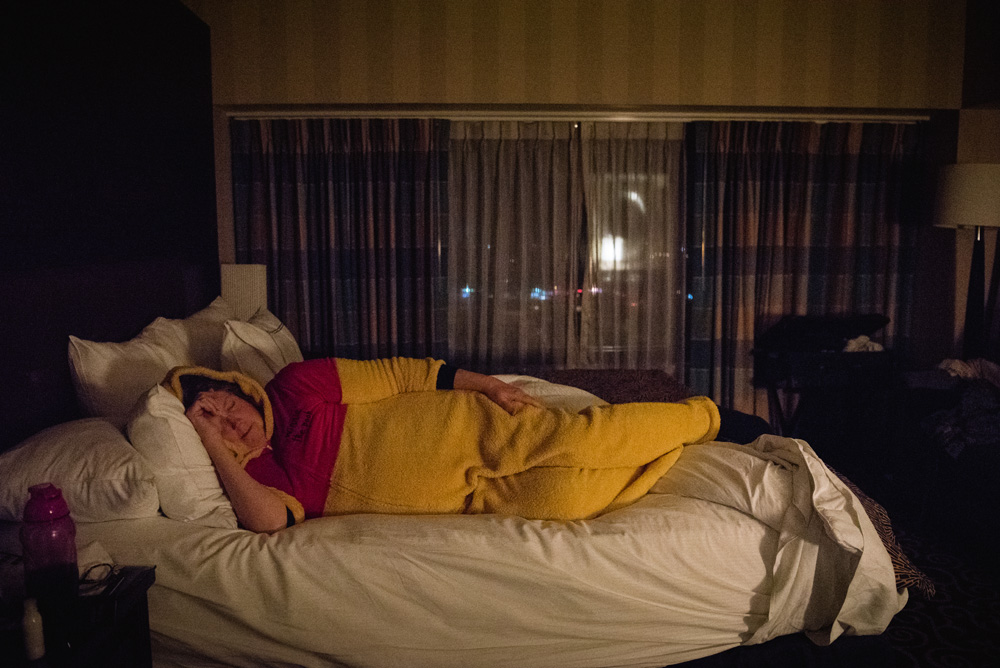 an adult woman laying on a bed in a room while wearing a winnie the pooh costume