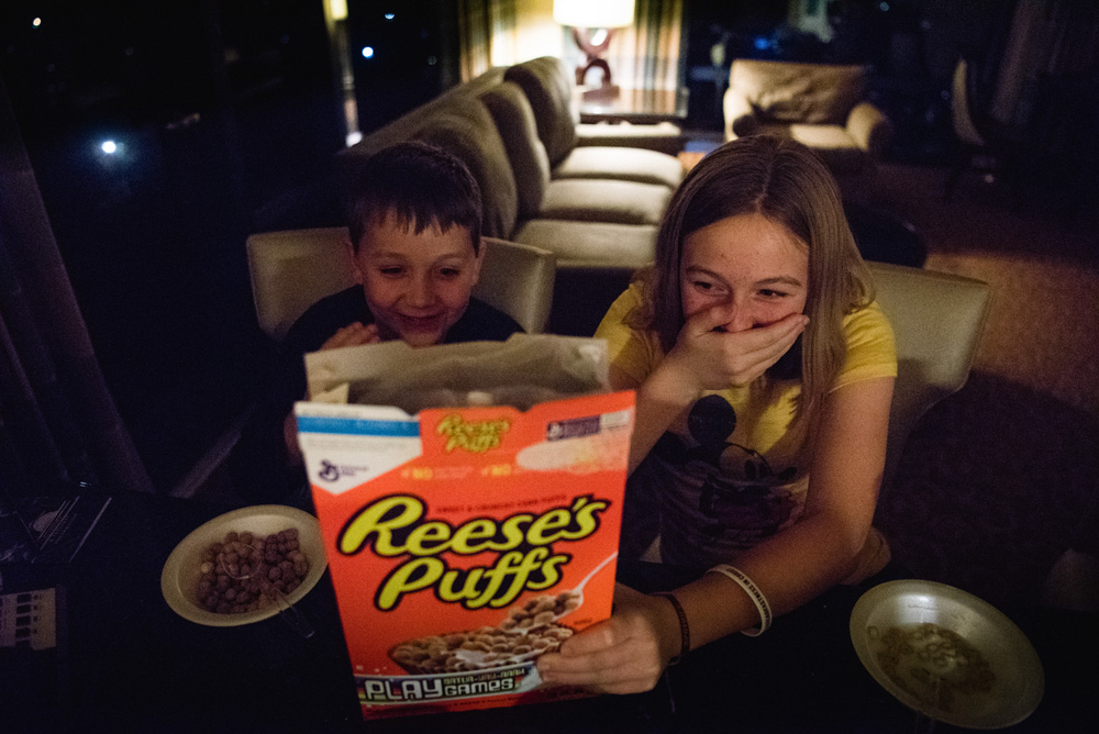 a boy and a girl eating reese's puffs cereal and laughing
